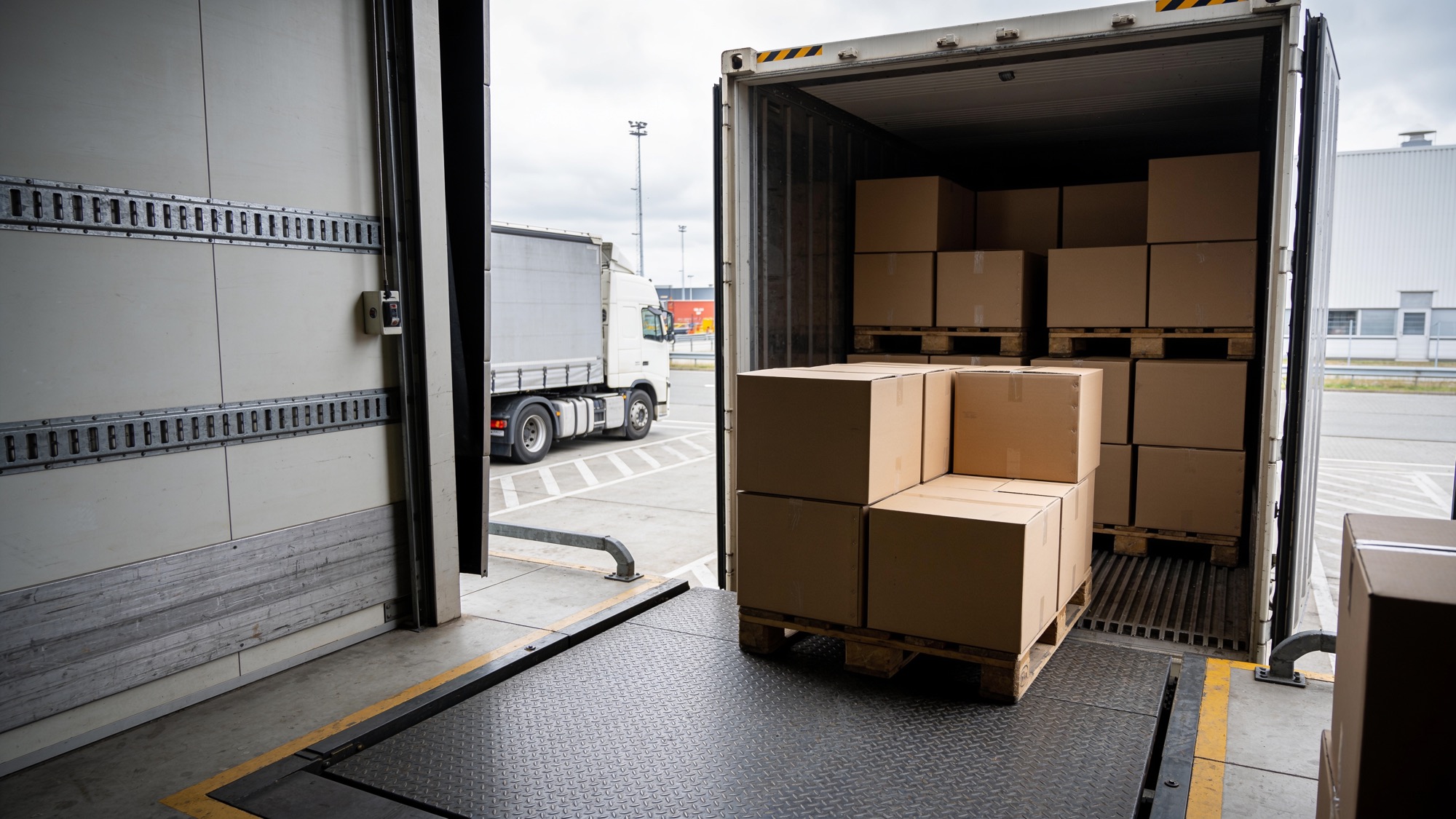 Een vrachtwagen bij een laadperron wordt geladen met pallets kartonnen dozen
